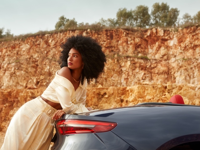 Темнокожая девушка стоит у автомобиля