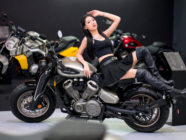 Брюнетка азиатка лежит на мотоцикле