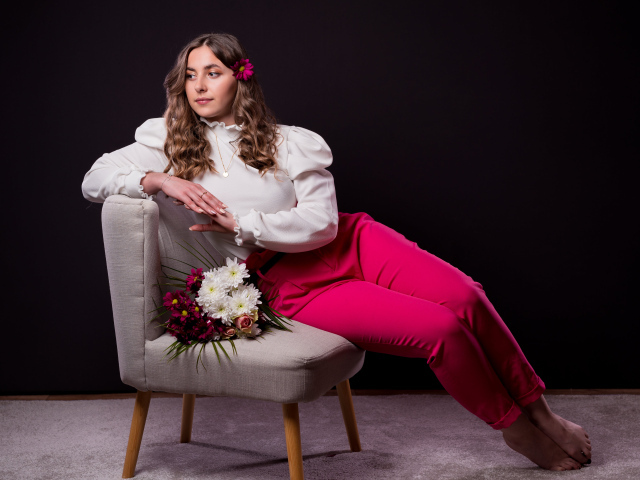 Милая девушка сидит на сером кресле с цветами