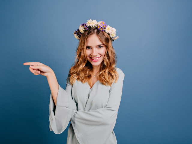 Милая улыбающаяся девушка с венком на голове на сером фоне