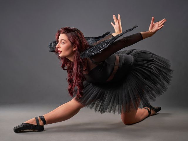 Девушка в черном костюме с крыльями танцует