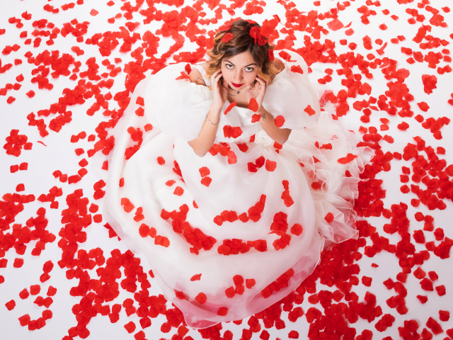 Девушка в белом платье сидит на лепестках розы