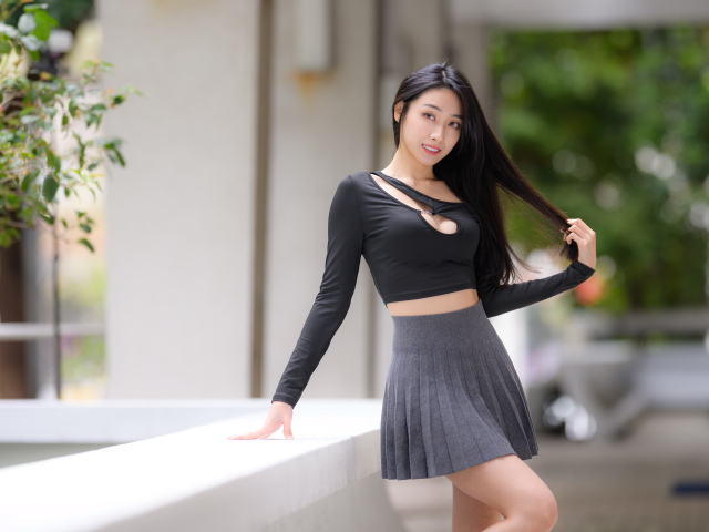 Молодая азиатка в короткой серой юбке