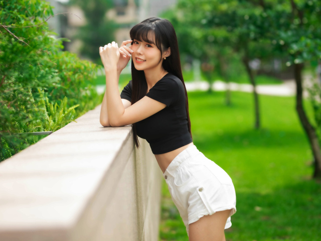 Молодая азиатка в белых шортах и футболке