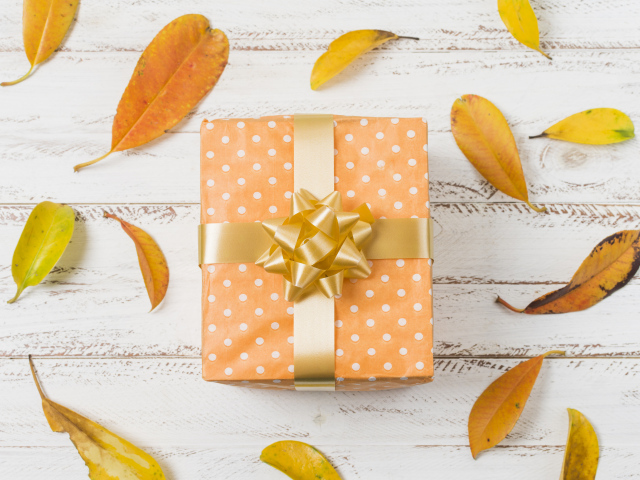 Подарок с желтыми листьями на белом фоне