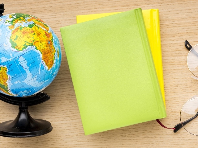 Глобус, тетради и очки на школьной парте