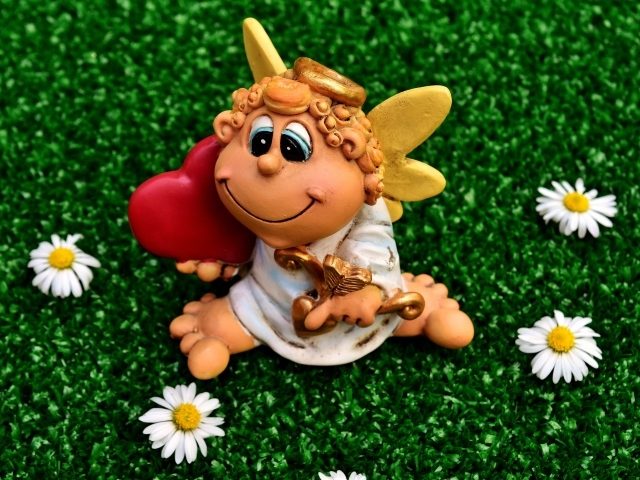 Статуэтка ангела на зеленой траве с белыми ромашками
