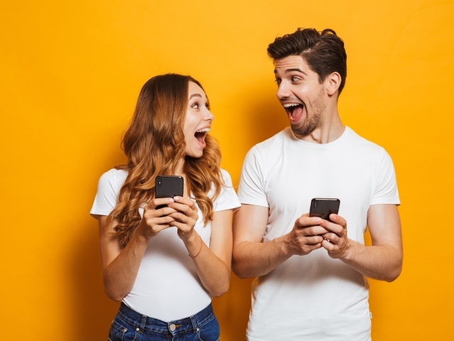 Счастливые парень и девушка с мобильными телефонами