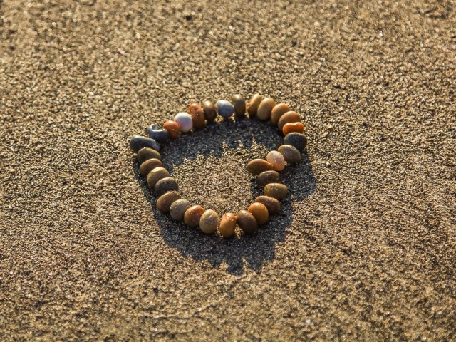 Сердце из камней на морском песке летом