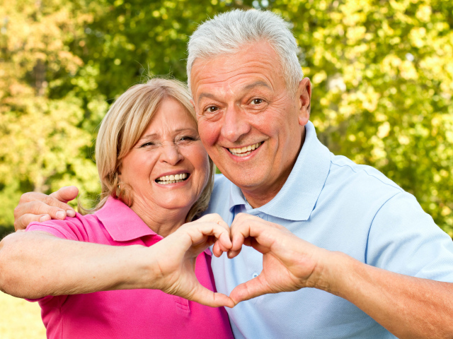 Улыбающаяся пара делает сердце руками