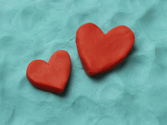 Два красных сердца из пластилина на голубом фоне