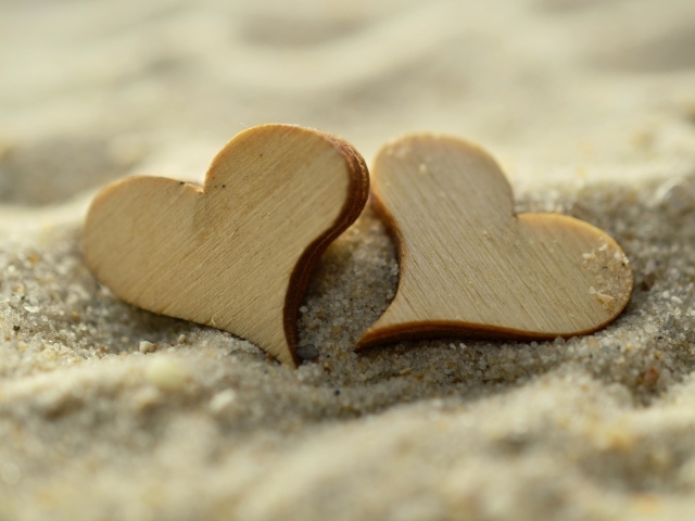 Два деревянных сердца лежат на песке на пляже