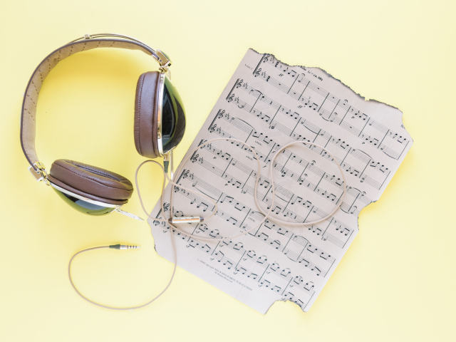 Старые ноты и наушники на желтом фоне
