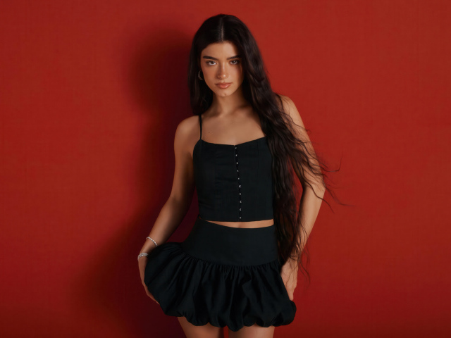 Популярная девушка Дикси Дамелио в черном костюме на красном фоне