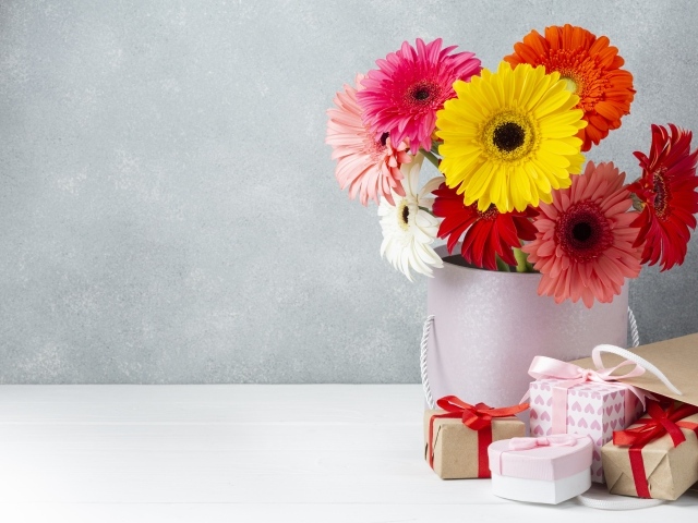 Букет разноцветных цветов герберы на столе с подарками