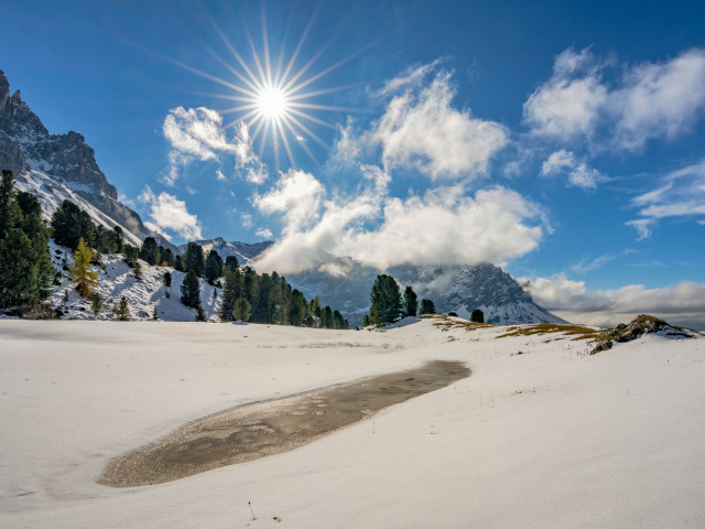 Яркое солнце над горами у заледеневшего озера