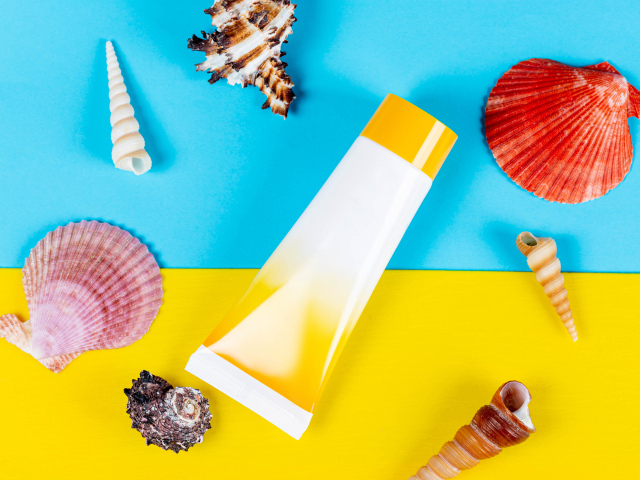 Крем от загара и ракушки на фоне