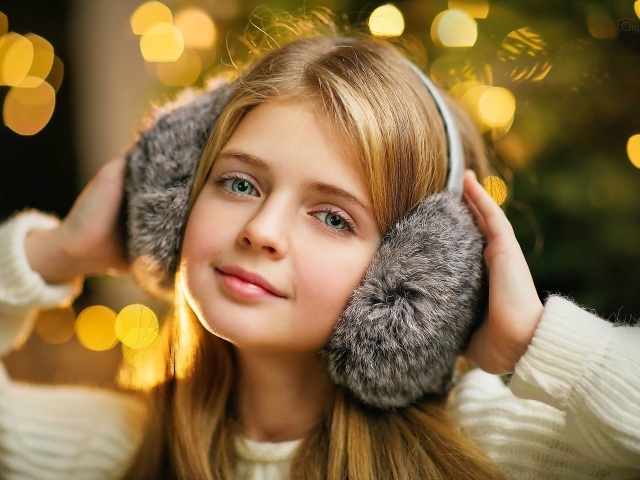 Красивая голубоглазая девочка в меховых наушниках