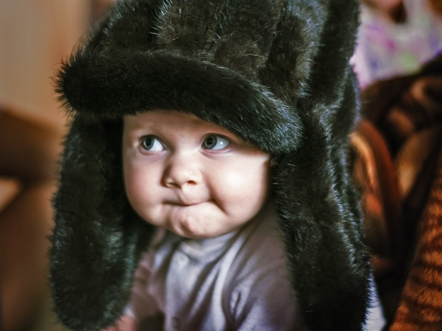 Смешной ребенок в черной меховой шапке
