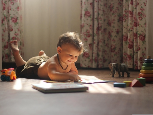 Маленький мальчик с игрушками читает книгу