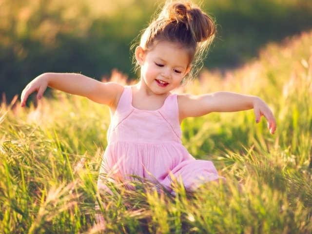 Маленькая девочка в розовом платье в зеленой траве