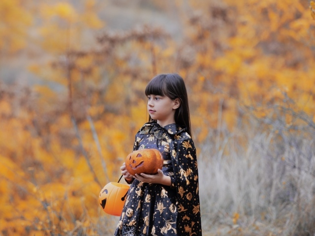 Маленькая девочка с тыквами в осеннем парке