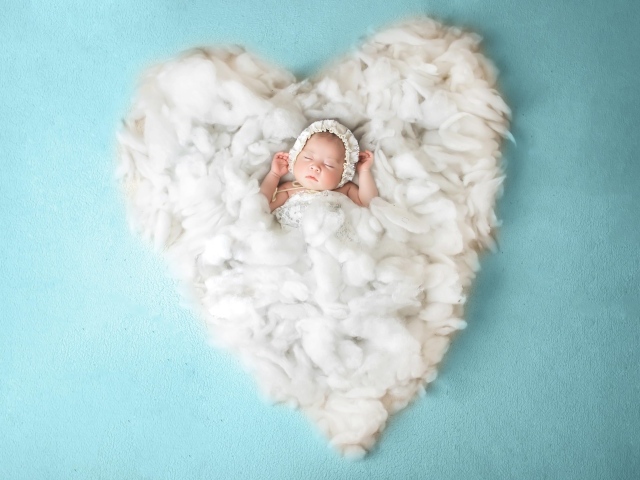 Новорожденный ребенок спит на белом мягком сердце на голубом фоне