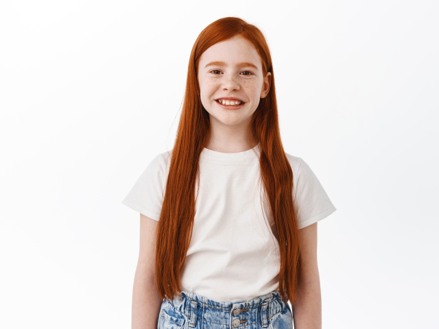 Улыбающаяся рыжеволосая девочка на белом фоне