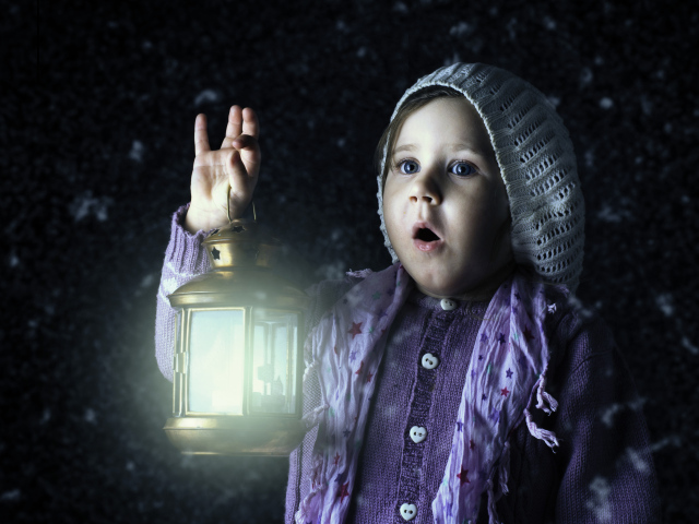 Удивленная маленькая девочка с фонарем в руках