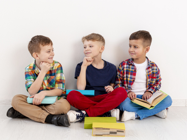 Три мальчика с книгами сидят у стены