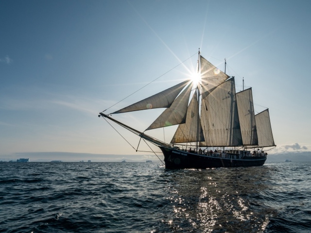 Корабль с белыми парусами в лучах солнца