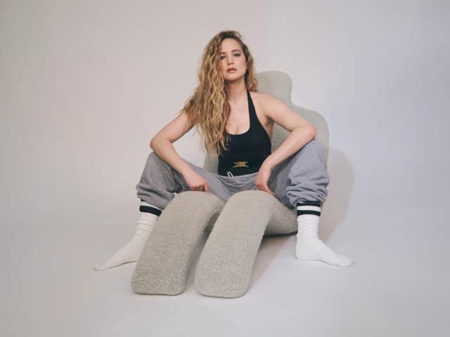 Красивая актриса Дженнифер Лоуренс  сидит на сером кресле