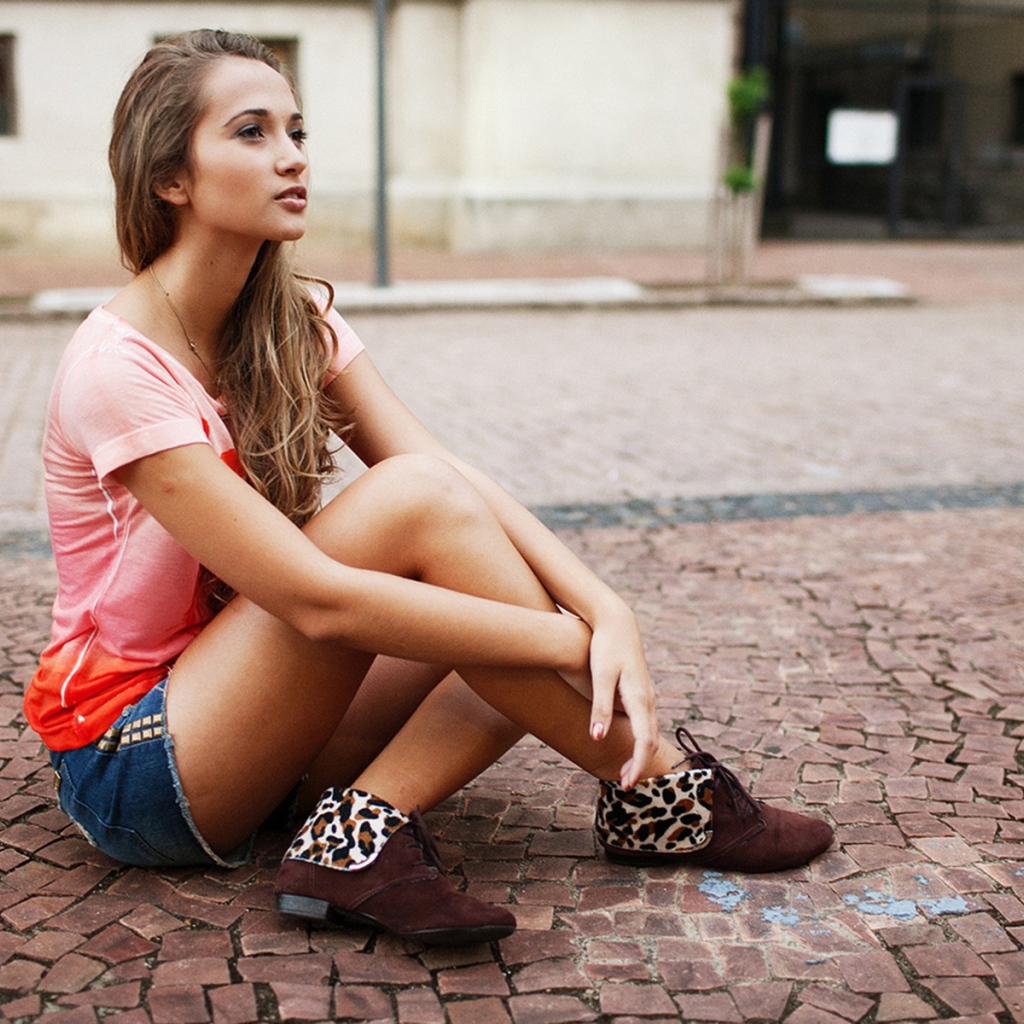 Брюнетка в шортах сидит на дороге