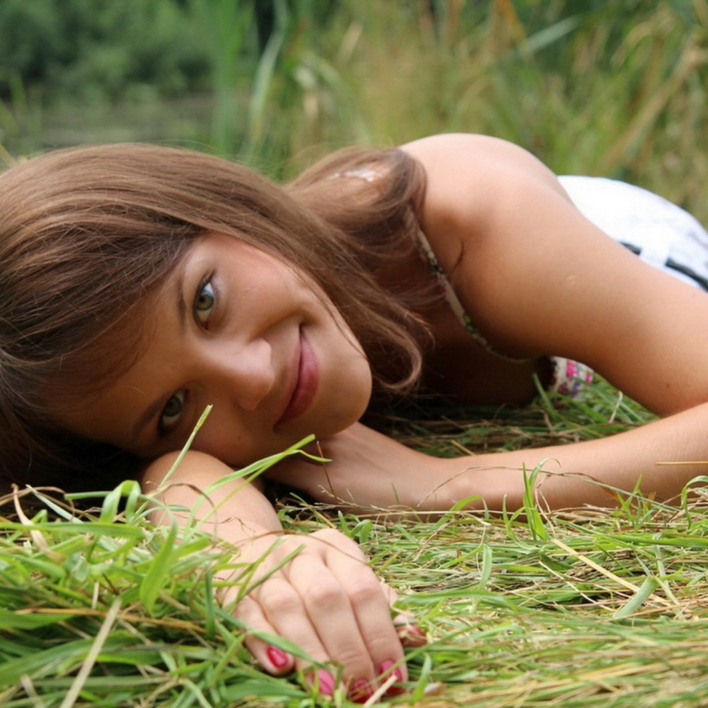 Девушка улыбается и лежит на траве
