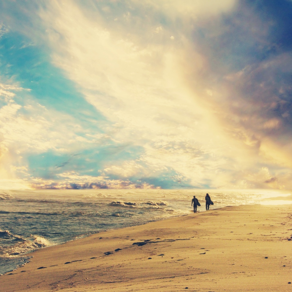 Двое идут по солнечному пляжу