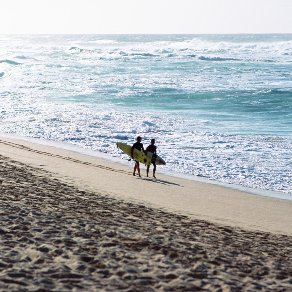 Два человека идут по пляжу