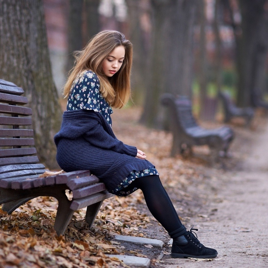 Симпатичная девушка сидит в осеннем парке