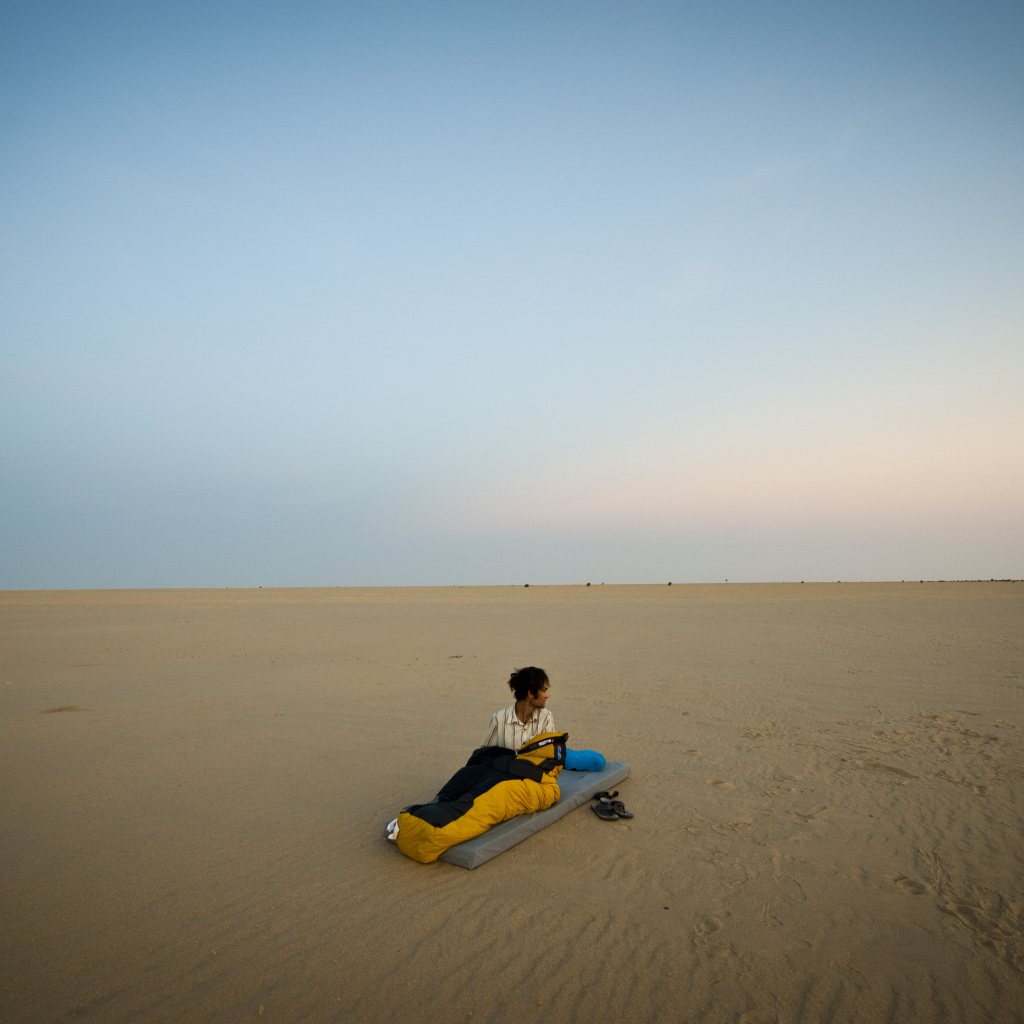 Мужчина на матрасе на пляже