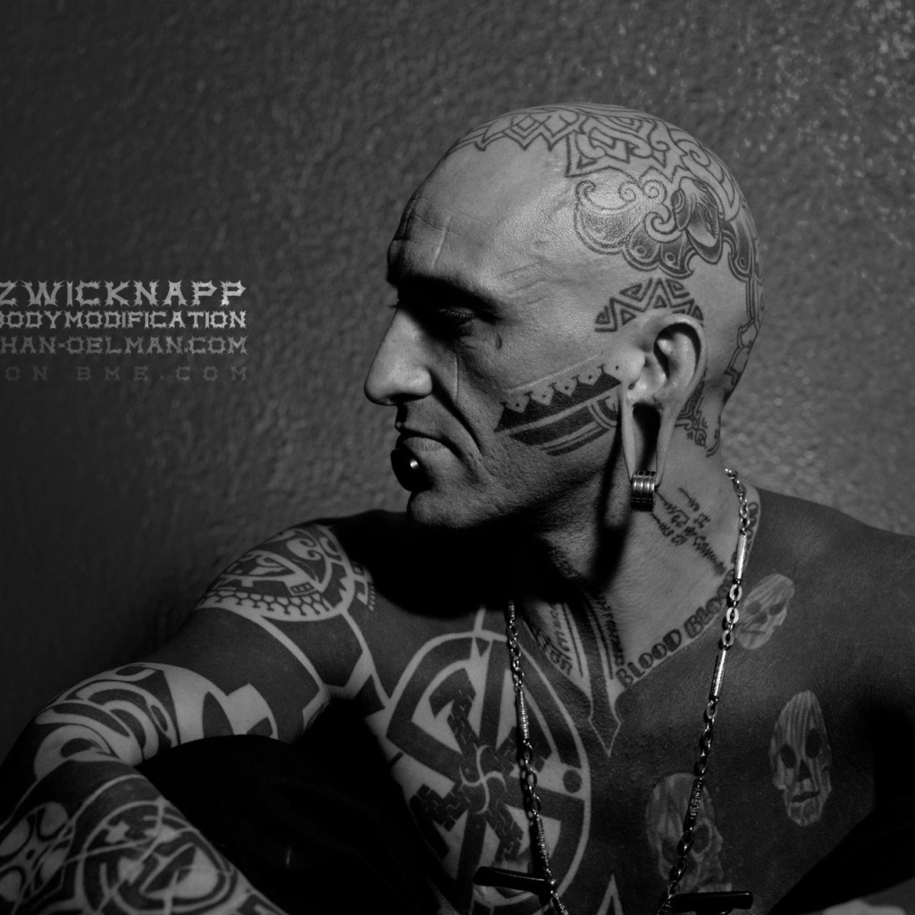 Мужчина с пирсингом в губе и татуировками