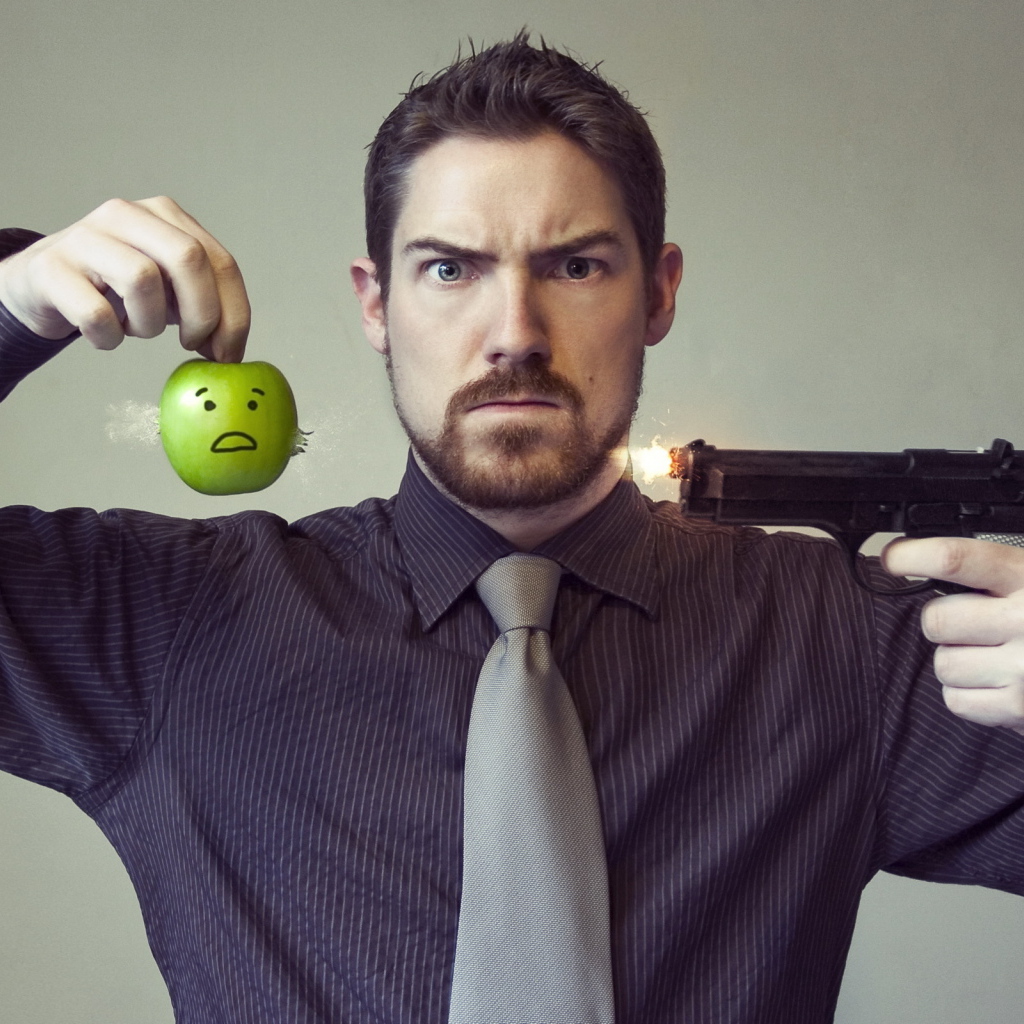 Мужчина стреляет в яблоко