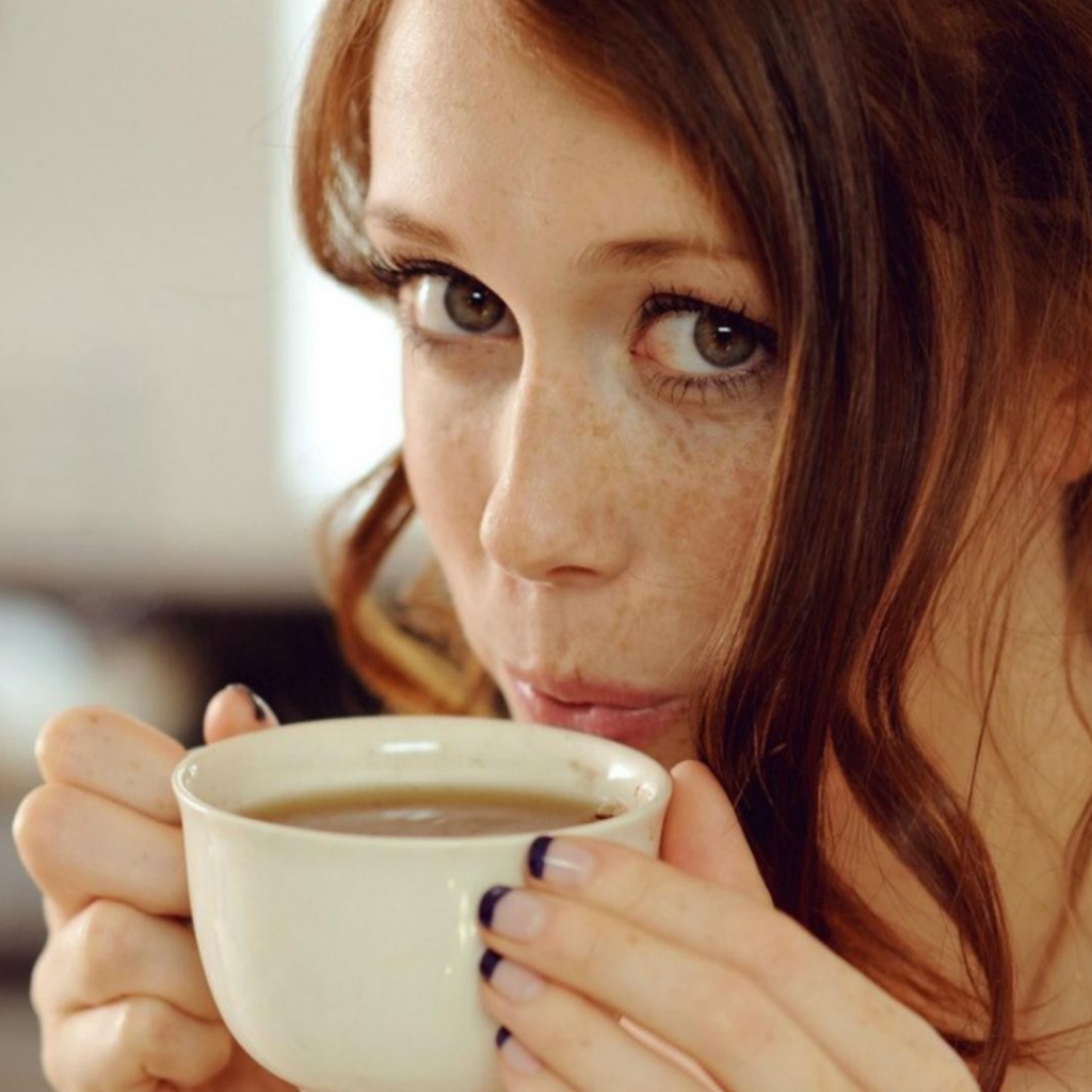 Девушка с веснушками пьет кофе