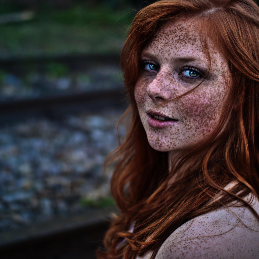 Девушка с веснушками на фоне рельс