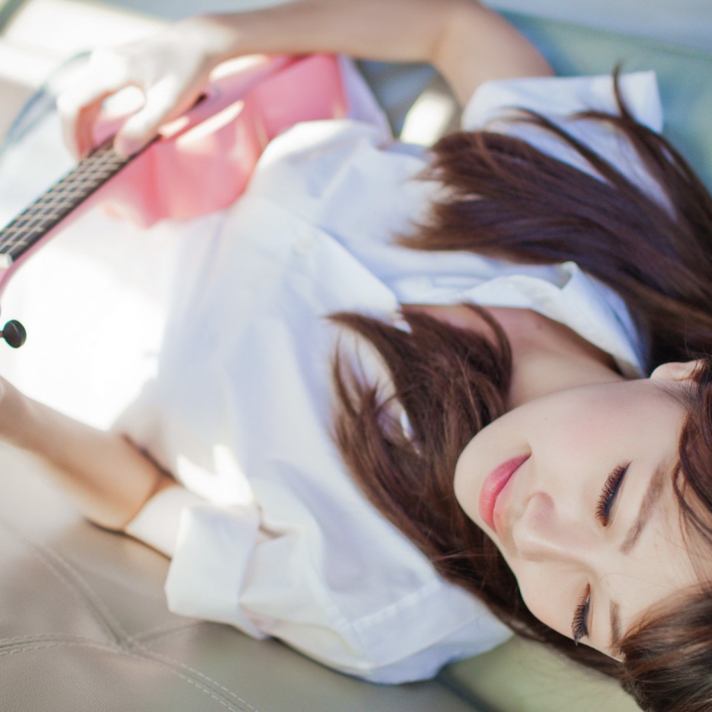 Брюнетка и розовая гитара на диване