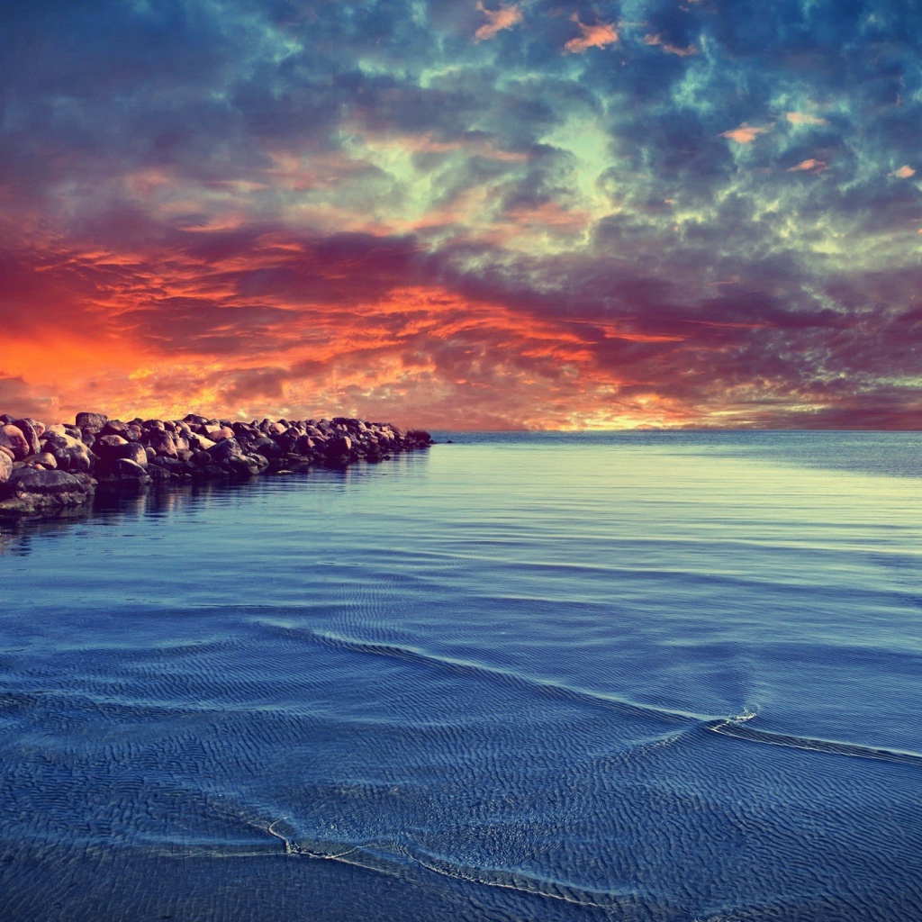 Красный закат над каменистым берегом