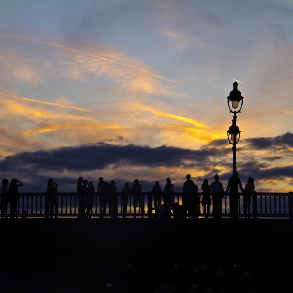 Люди провожают солнце на мосту