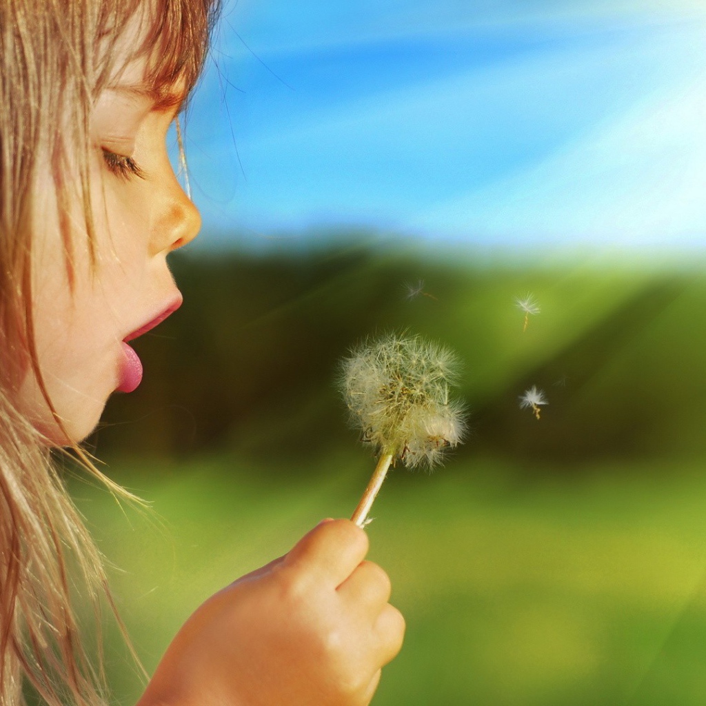 Девочка дует на одуванчик