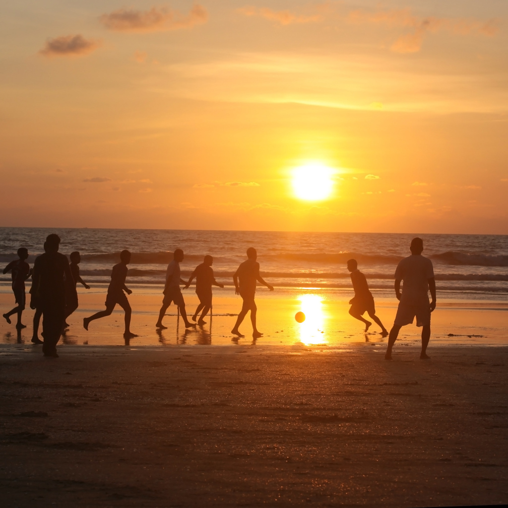 Парни играют в футбол на пляже в Гоа