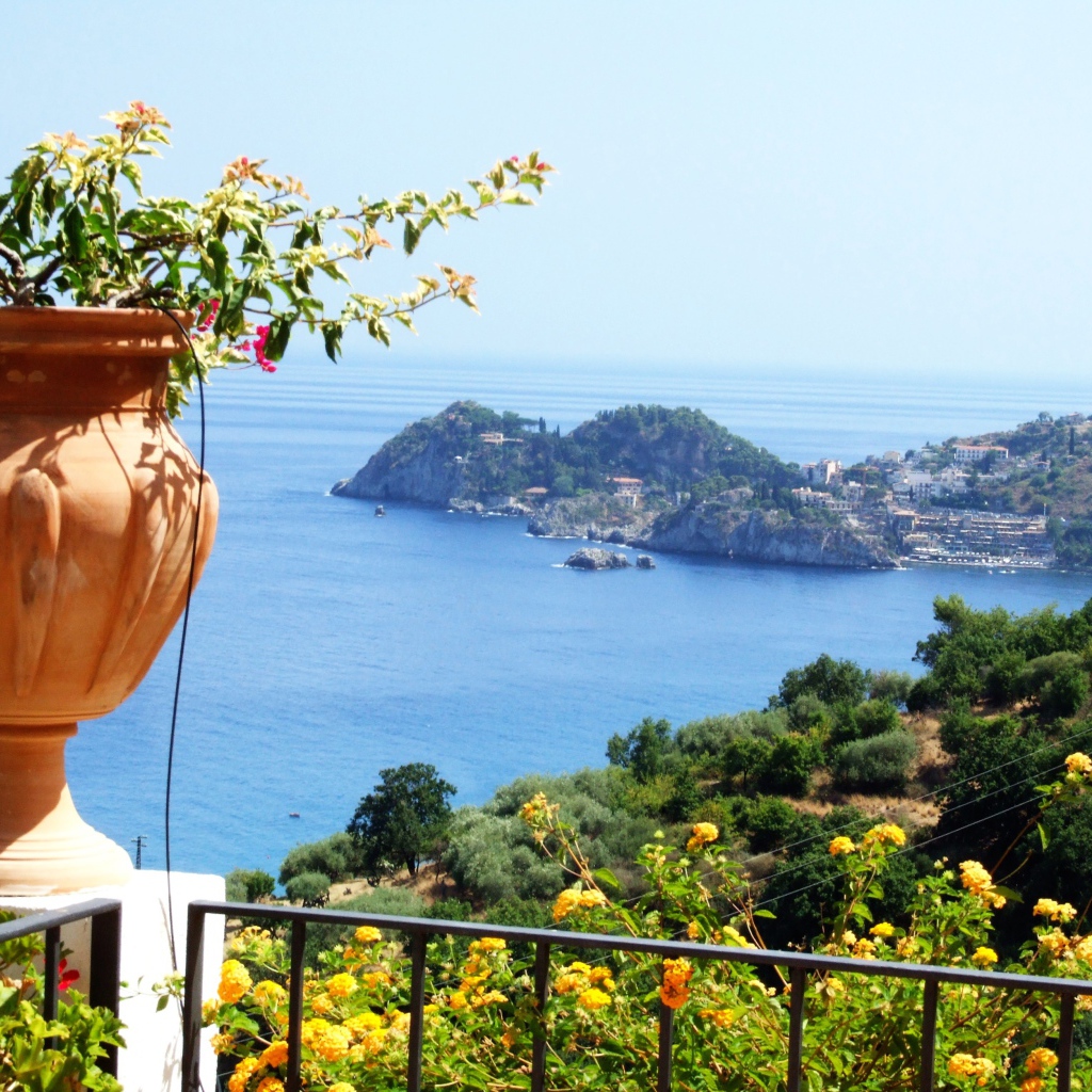 Кувшин с цветами на фоне залива на острове Сицилия, Италия