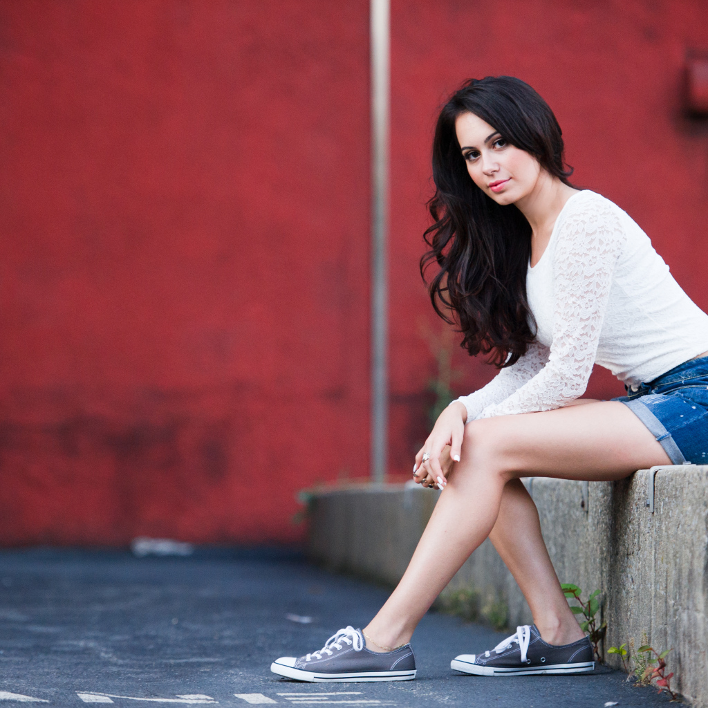 Брюнетка в кедах на бордюре
