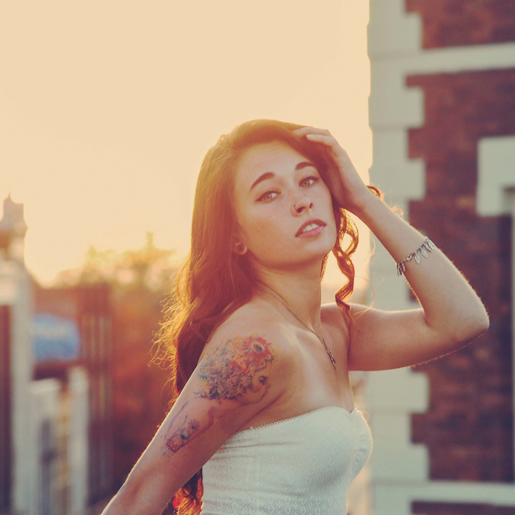Девушка на закате с татуировкой на плече